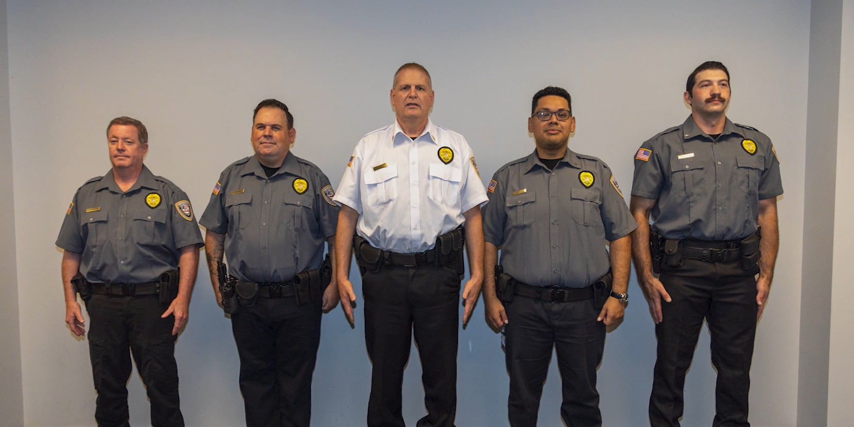 Five Securemedy officers in grey and white uniforms standing in a line