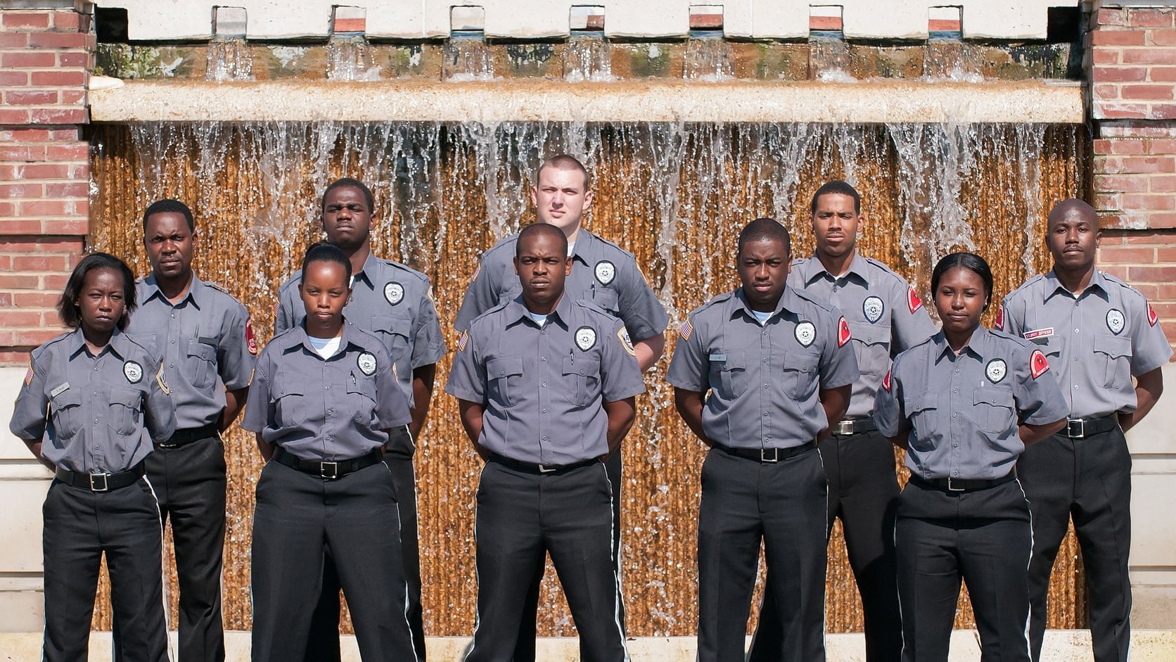 Team of Securemedy officers in grey uniforms standing in front of a fountain