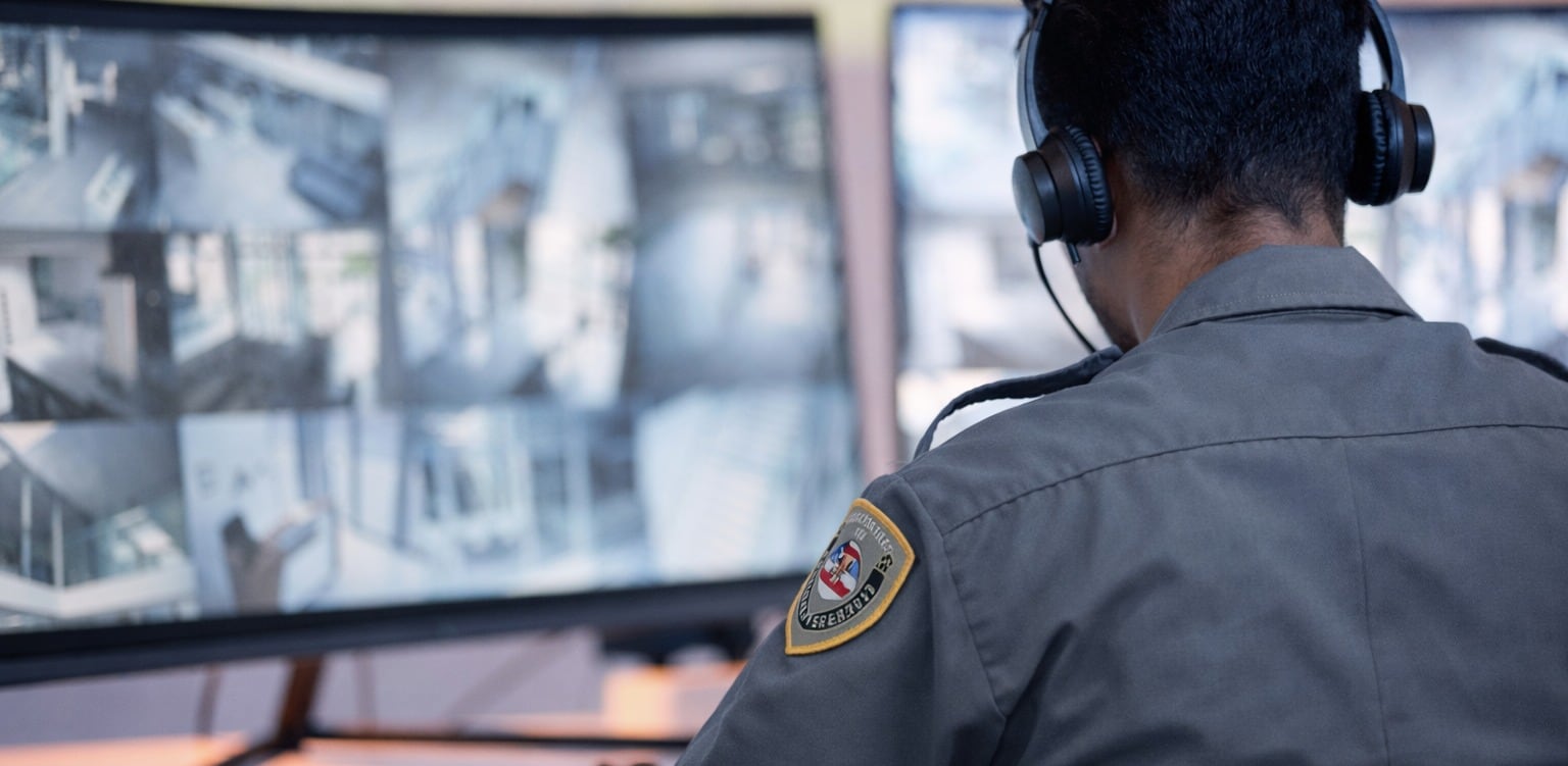 Securemedy officer with a headset monitoring surveillance camera feeds