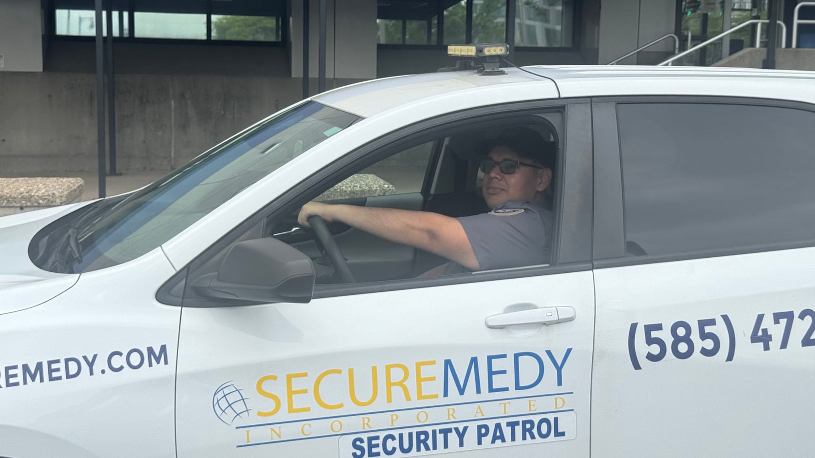 Securemedy officer driving a marked Securemedy Security Patrol vehicle