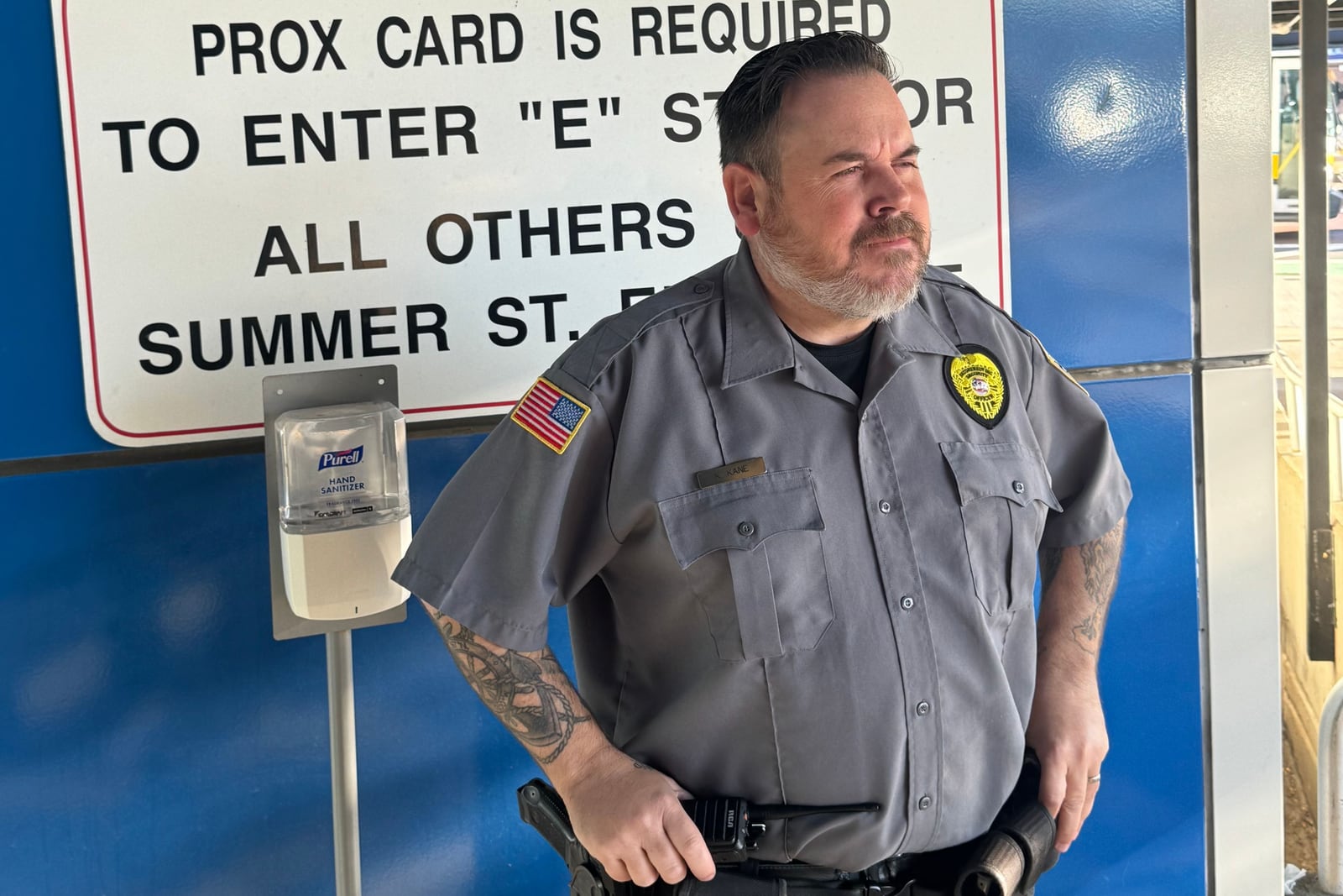 Securemedy officer in a grey uniform standing post at a building entrance