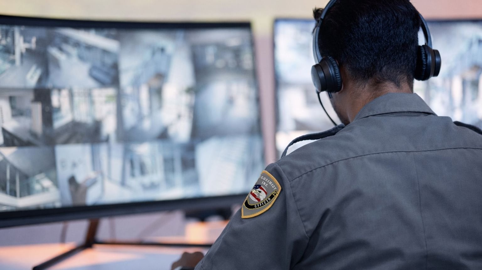 Securemedy officer in a grey uniform monitoring surveillance camera feeds